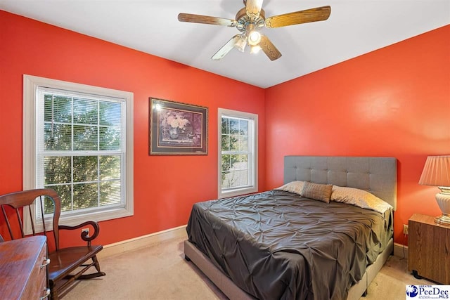 carpeted bedroom featuring multiple windows and ceiling fan