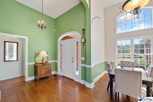 entrance foyer with wood-type flooring, high vaulted ceiling, and a chandelier