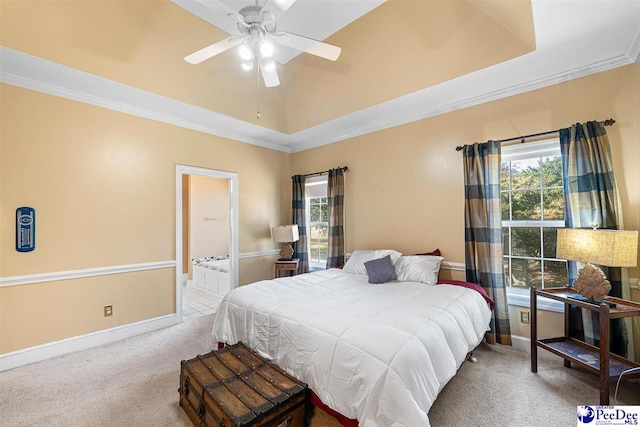 carpeted bedroom featuring crown molding, a tray ceiling, ceiling fan, and ensuite bathroom