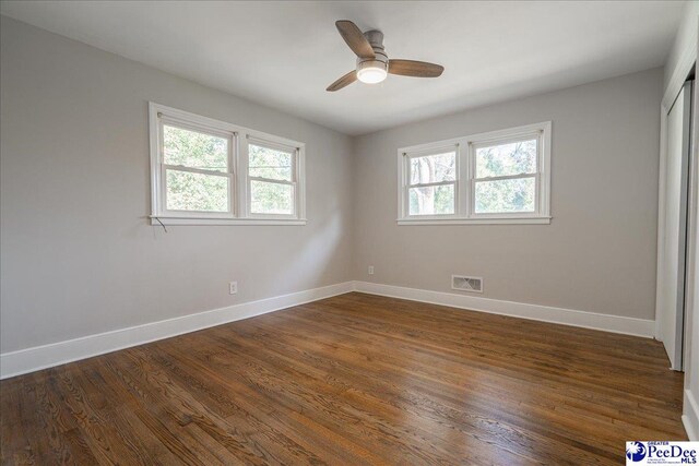 unfurnished room featuring dark wood-type flooring, ceiling fan, and plenty of natural light