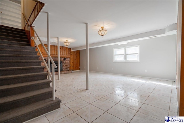 basement featuring light tile patterned floors and wood walls