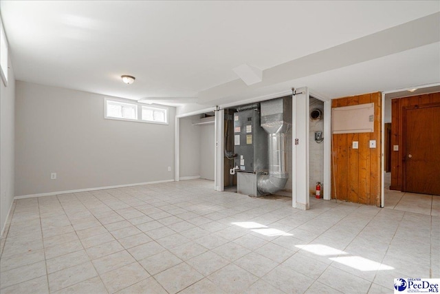 basement featuring light tile patterned floors and wood walls