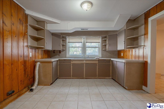 kitchen featuring sink, light tile patterned floors, and wooden walls