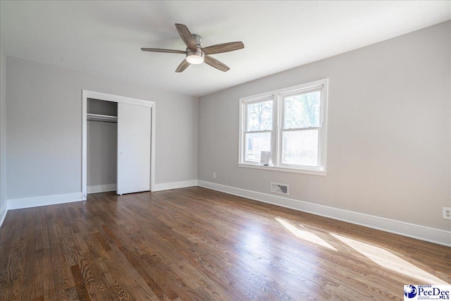 unfurnished bedroom with dark wood-type flooring, a closet, and ceiling fan