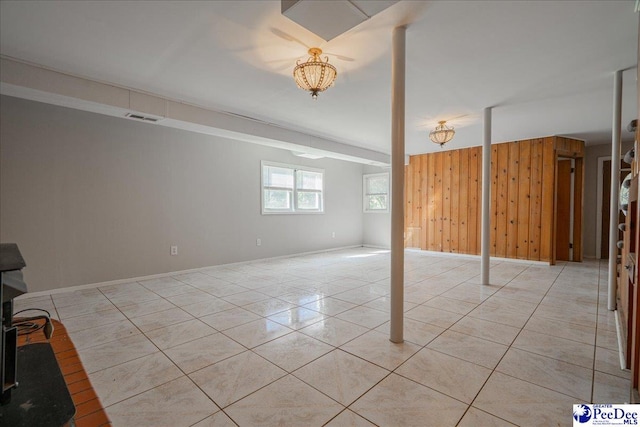 basement with light tile patterned flooring and wood walls