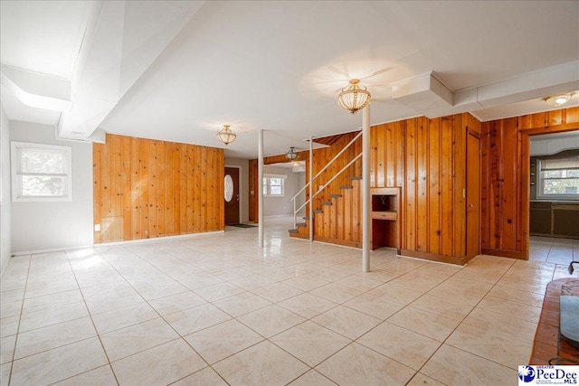 unfurnished living room with wooden walls and light tile patterned flooring