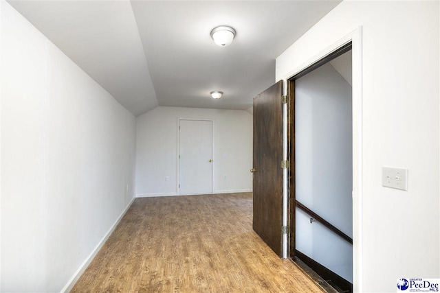 corridor featuring lofted ceiling and light hardwood / wood-style flooring