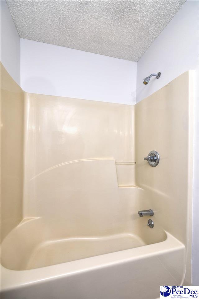 bathroom featuring shower / bathtub combination and a textured ceiling