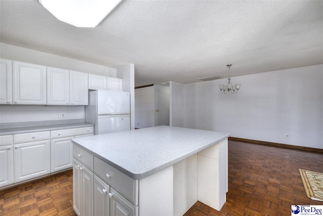 kitchen featuring dark parquet flooring, white cabinetry, hanging light fixtures, a kitchen island, and white fridge