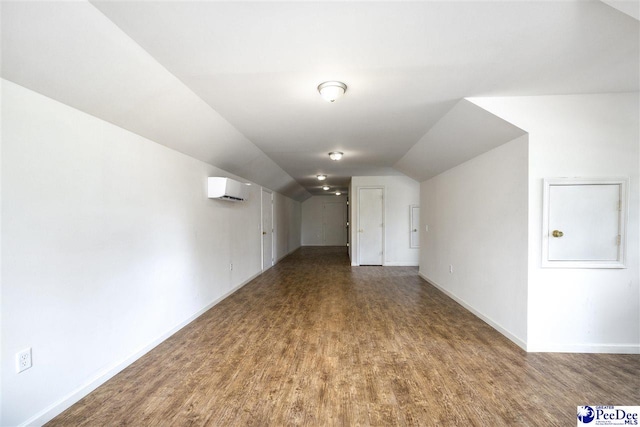 additional living space featuring lofted ceiling, wood-type flooring, and a wall unit AC