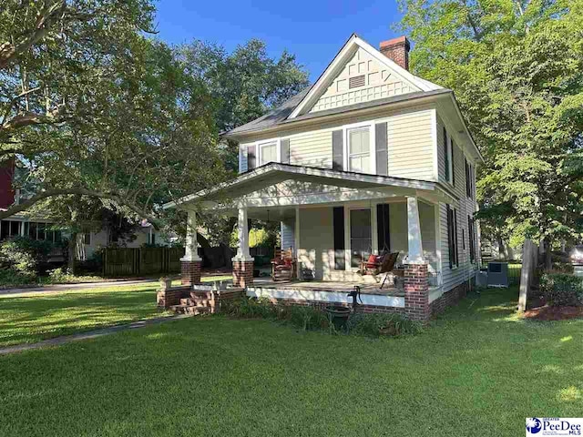 view of front of property featuring cooling unit, a front yard, and a porch