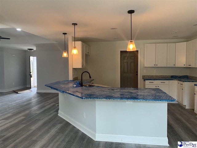 kitchen featuring hanging light fixtures, a peninsula, white cabinetry, and a sink