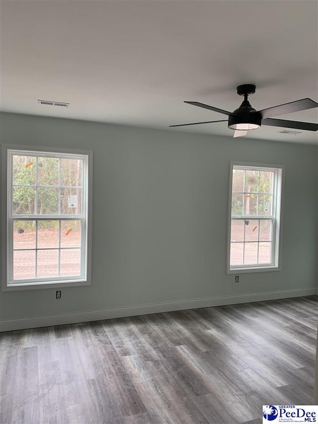 spare room with a ceiling fan, visible vents, baseboards, and wood finished floors