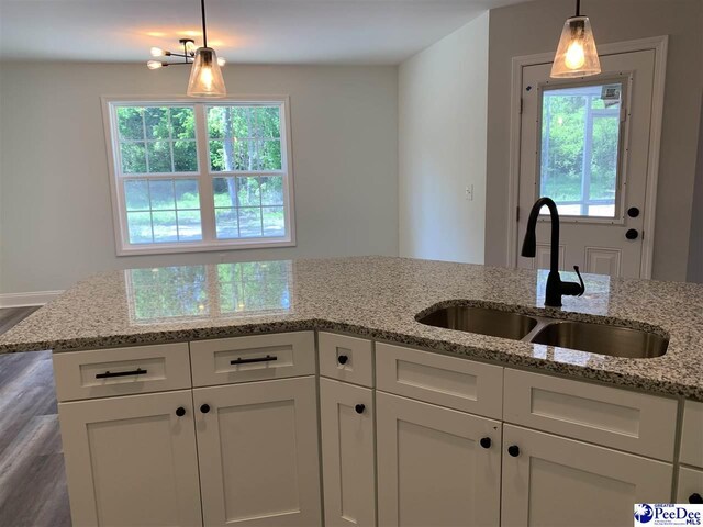 7423 E National Cemetery Rd, Florence, SC 29506 - kitchen with a sink, white cabinetry, wood finished floors, light stone counters, and pendant lighting