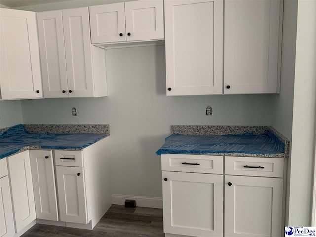 kitchen featuring dark wood-style flooring, white cabinetry, and baseboards