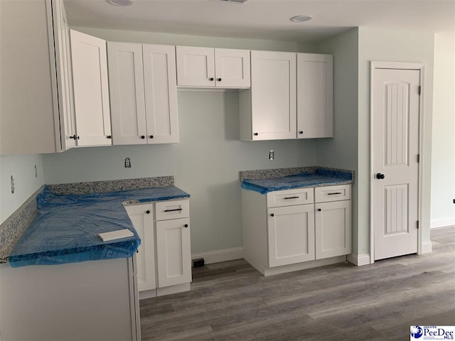 kitchen with baseboards, dark countertops, white cabinetry, and light wood-style floors