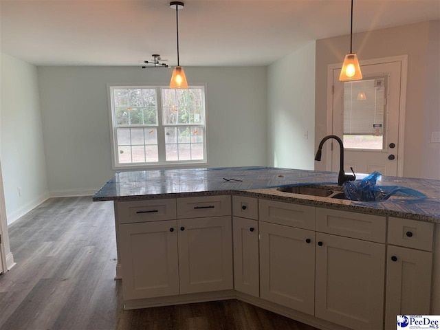 kitchen featuring stone counters, white cabinetry, and hanging light fixtures