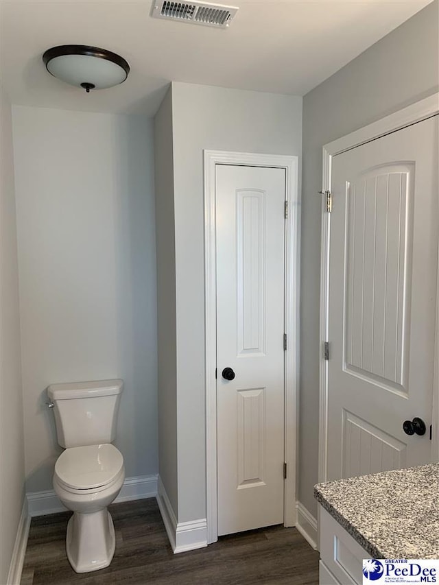 7423 E National Cemetery Rd, Florence, SC 29506 - bathroom with wood finished floors, toilet, baseboards, and vanity