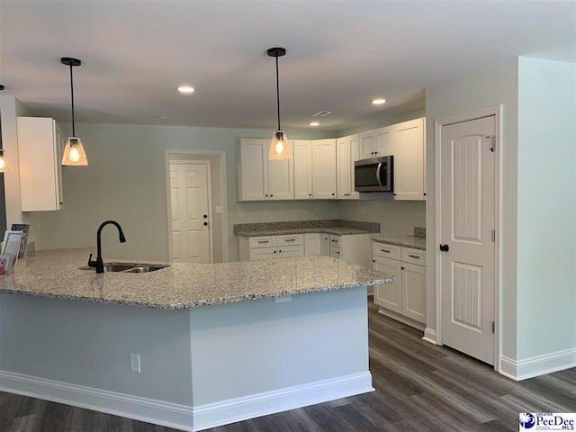 7423 E National Cemetery Rd, Florence, SC 29506 - kitchen with stainless steel microwave, a sink, a peninsula, light stone countertops, and dark wood-style flooring
