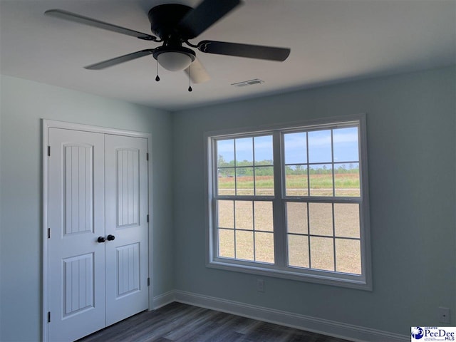 7423 E National Cemetery Rd, Florence, SC 29506 - unfurnished bedroom featuring dark wood-style floors, multiple windows, a closet, and baseboards