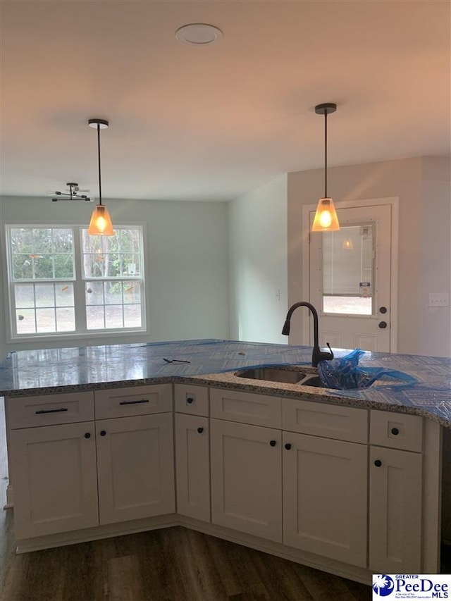 kitchen featuring hanging light fixtures, light stone countertops, and a sink