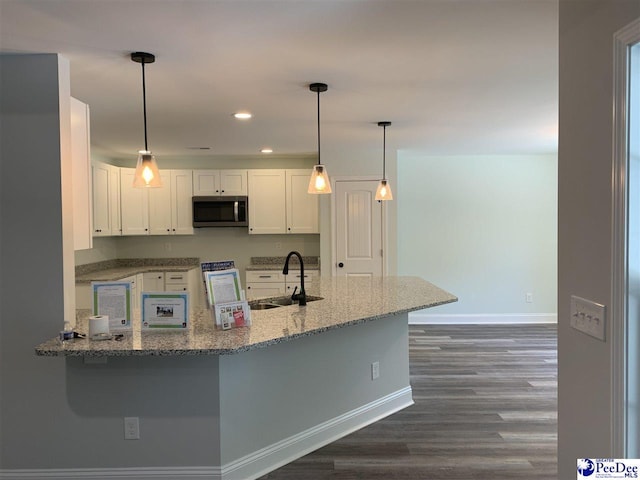 7423 E National Cemetery Rd, Florence, SC 29506 - kitchen with a sink, stainless steel microwave, baseboards, light stone countertops, and white cabinetry