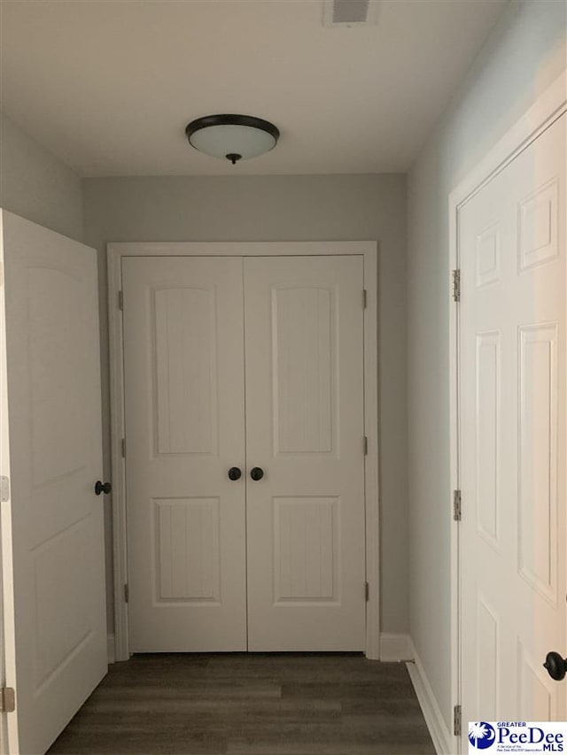 hallway with dark wood-style flooring, visible vents, and baseboards