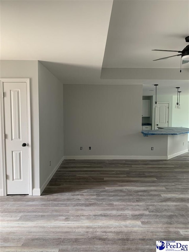 unfurnished living room featuring ceiling fan, wood finished floors, and baseboards