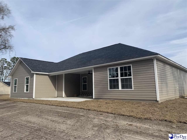 single story home featuring a shingled roof and a patio area