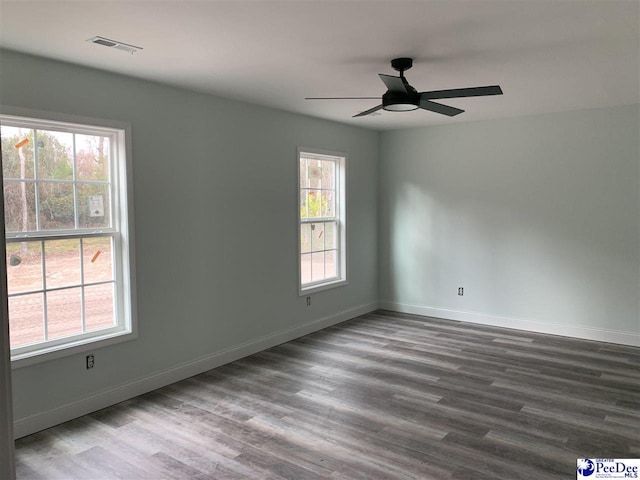 unfurnished room featuring a ceiling fan, baseboards, visible vents, and wood finished floors