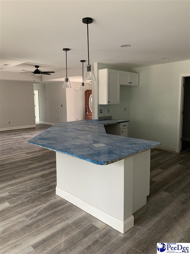 kitchen with dark wood-type flooring, white cabinets, decorative light fixtures, and a ceiling fan