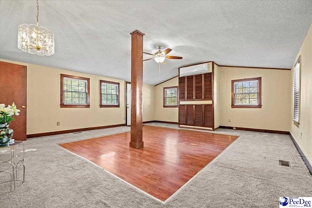 unfurnished living room featuring lofted ceiling, a wall mounted air conditioner, a wealth of natural light, and light carpet