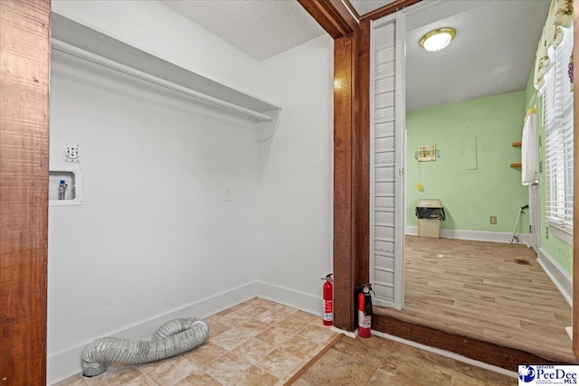 clothes washing area featuring hookup for a washing machine and a textured ceiling