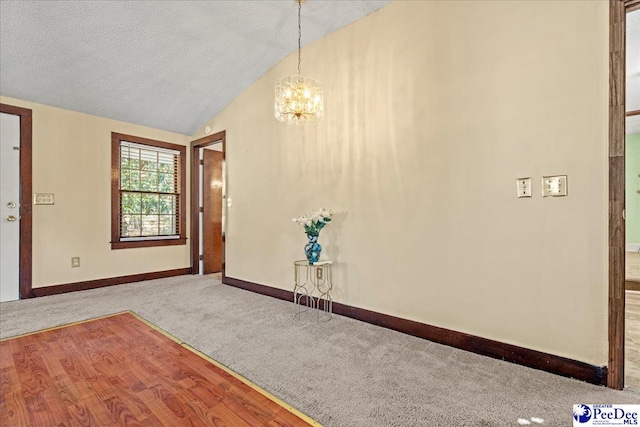 interior space with vaulted ceiling, carpet floors, a textured ceiling, and a notable chandelier