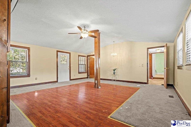 unfurnished living room featuring ceiling fan, lofted ceiling, wood-type flooring, and a textured ceiling