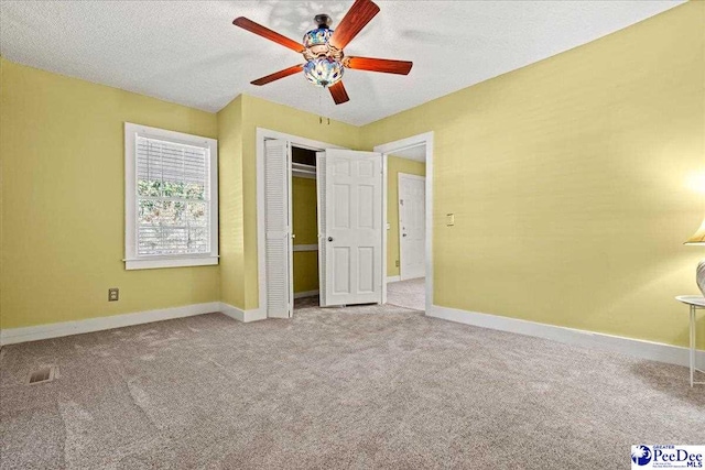 unfurnished bedroom featuring ceiling fan, carpet floors, a closet, and a textured ceiling