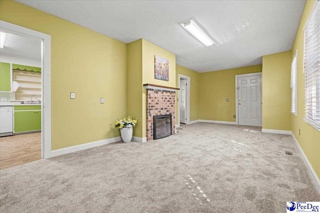 unfurnished living room with sink, a fireplace, a textured ceiling, and carpet