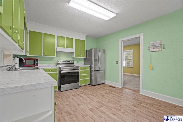 kitchen featuring sink, light hardwood / wood-style flooring, green cabinets, appliances with stainless steel finishes, and a textured ceiling