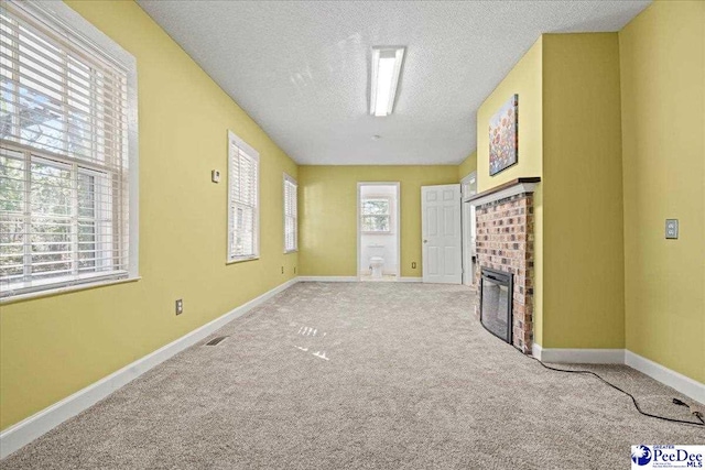 unfurnished living room with a brick fireplace, light colored carpet, and a textured ceiling