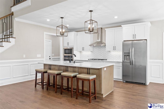 2104 Lacy St, Florence, SC 29505 - kitchen with stainless steel appliances, wall chimney exhaust hood, a center island with sink, crown molding, and white cabinets