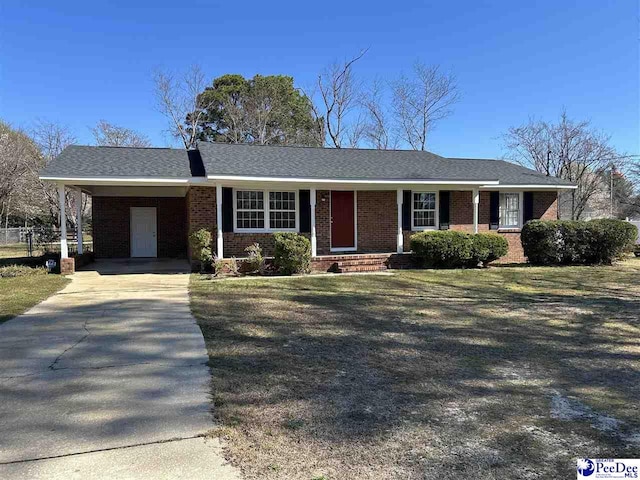 single story home with driveway, an attached carport, a front yard, a shingled roof, and brick siding