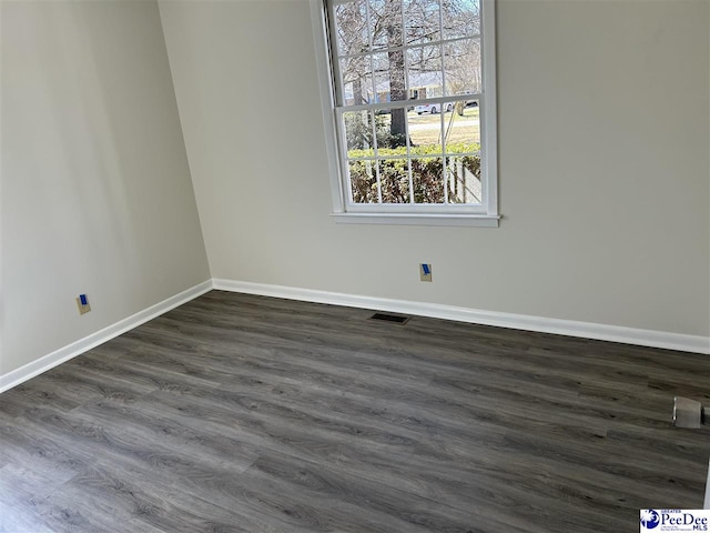 spare room with dark wood-type flooring, baseboards, and visible vents