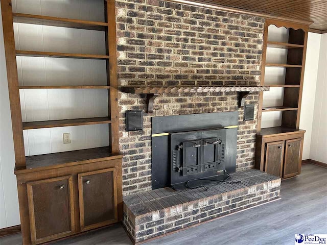 details featuring a wood stove, built in shelves, wood finished floors, and baseboards