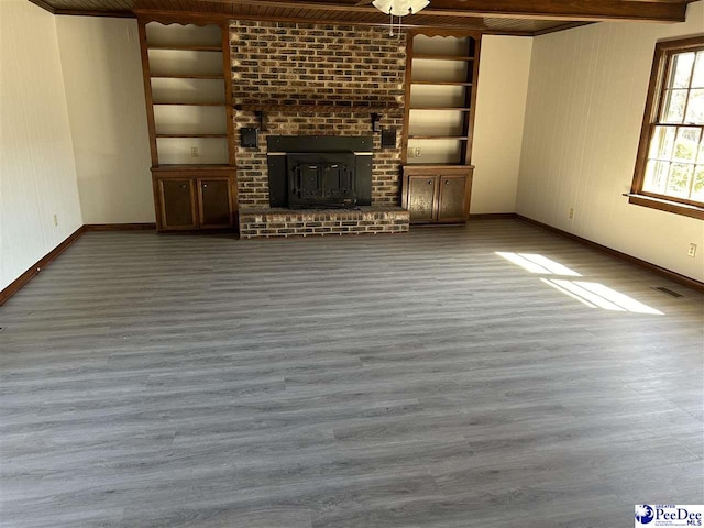 unfurnished living room with built in features, baseboards, and wood finished floors