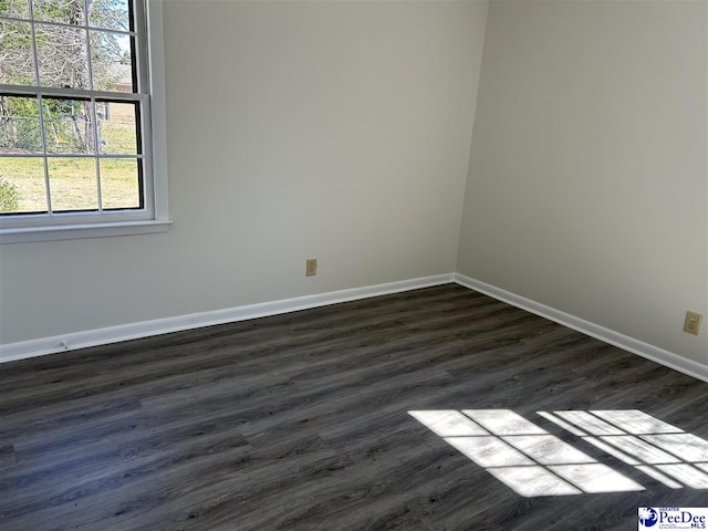 spare room featuring baseboards and dark wood-style flooring