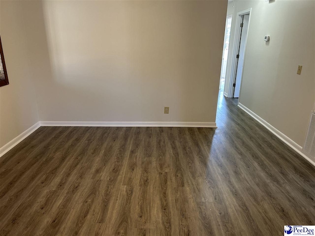 empty room with dark wood finished floors and baseboards