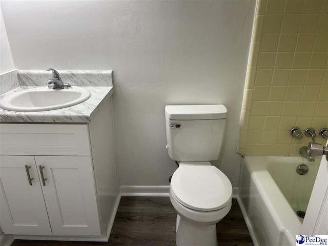 bathroom with toilet, vanity, baseboards, and wood finished floors