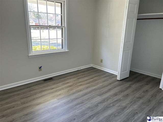 unfurnished bedroom with visible vents, baseboards, a closet, and dark wood-style flooring