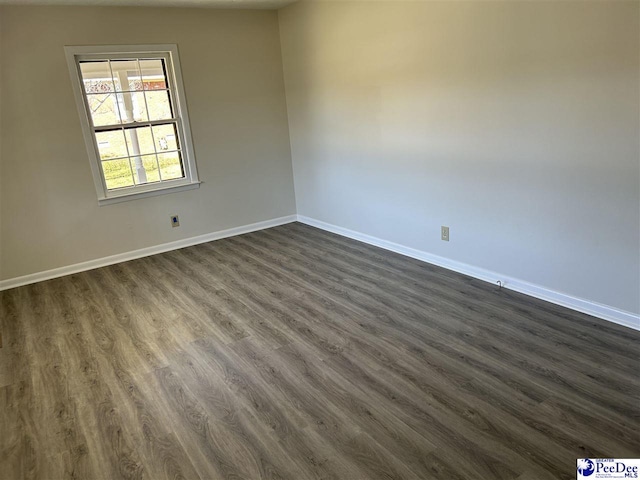 spare room featuring baseboards and dark wood finished floors