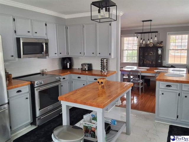 kitchen with wood counters, hanging light fixtures, crown molding, and stainless steel appliances